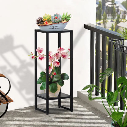 Black metal plant stand with two levels, holding succulents and flowers on a balcony or patio.